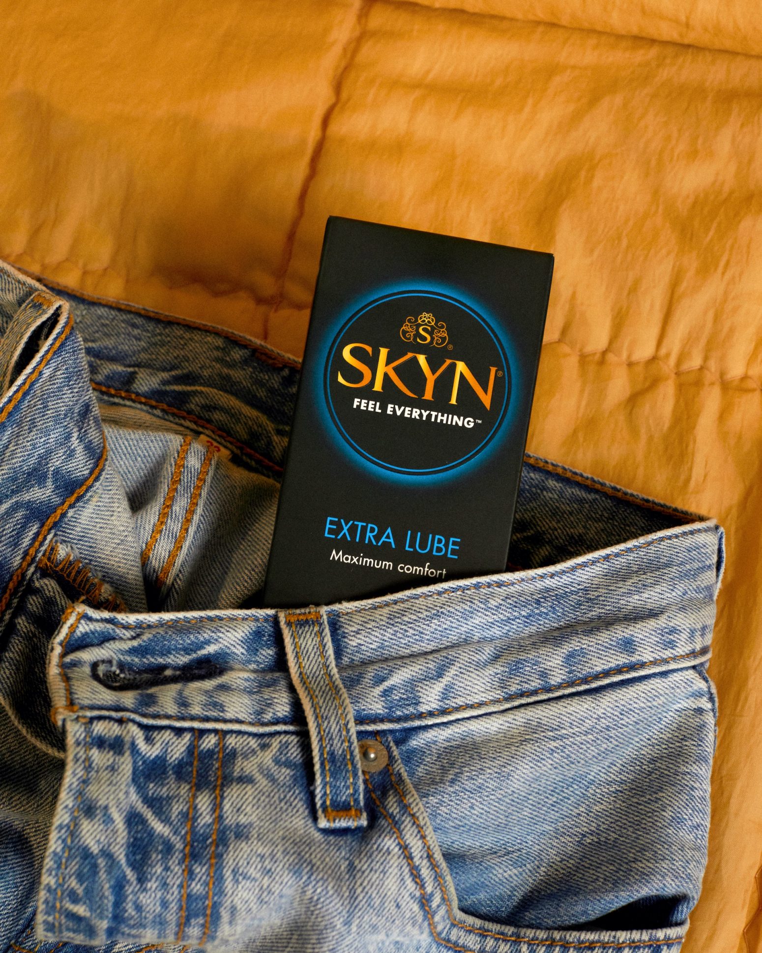 SKYN Extra Lube condom box inside a pair of blue jeans