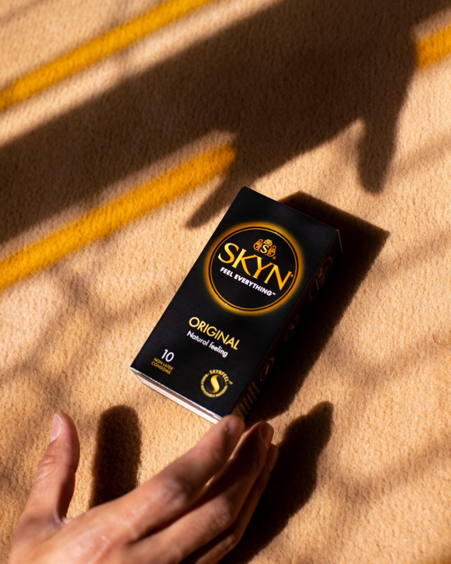 Hand reaching a box of SKYN Original condom box