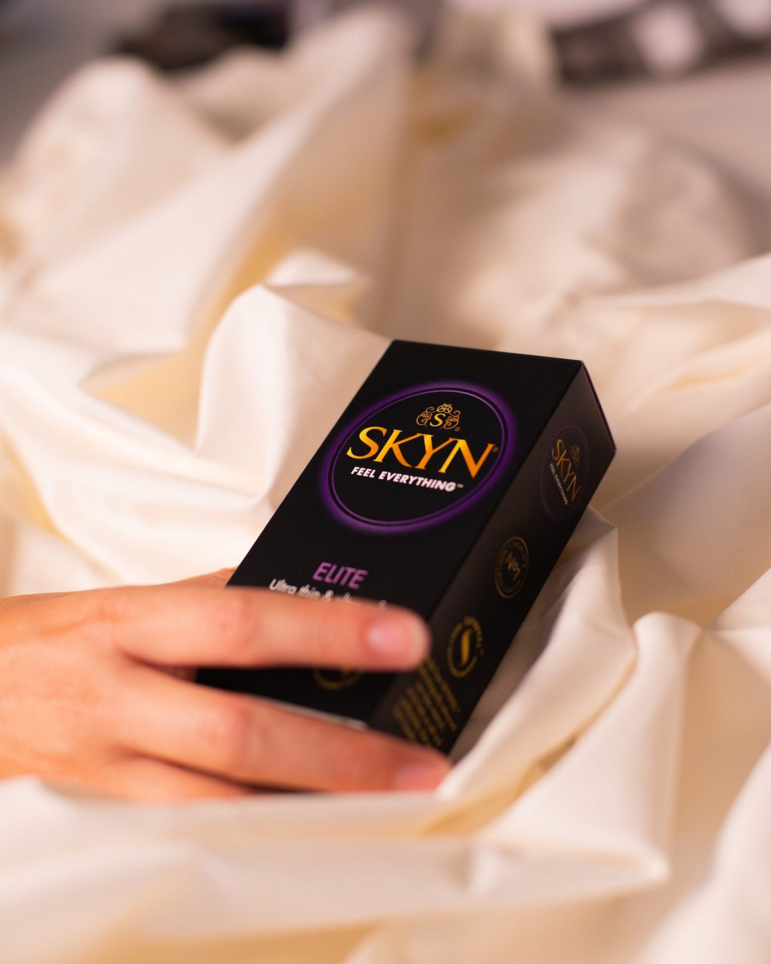 Hand reaching over a SKYN Elite condom box