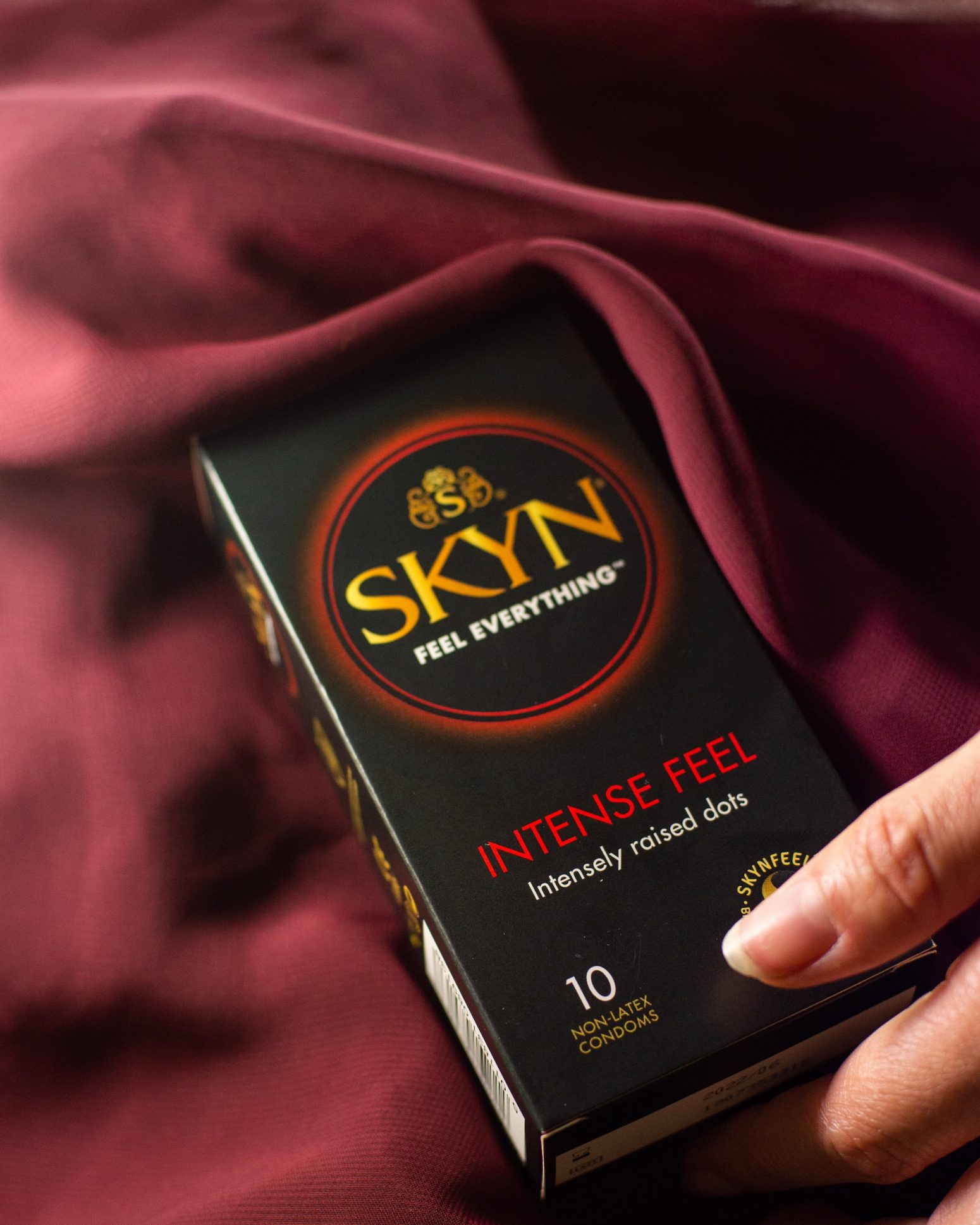 Hand reaching SKYN Intense Feel condom box