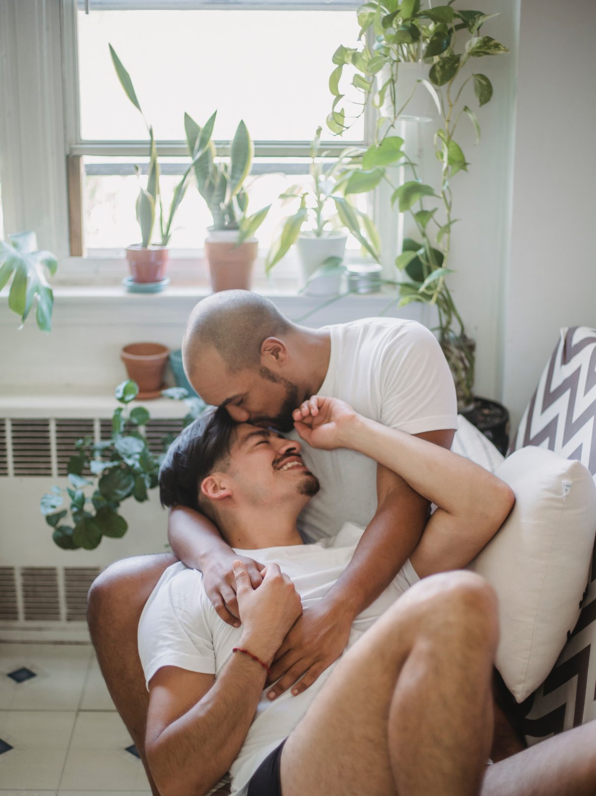 A man smiling in the arms of his partner in the bathroom